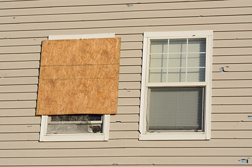 exterior house with boarded-up windows from hail damage